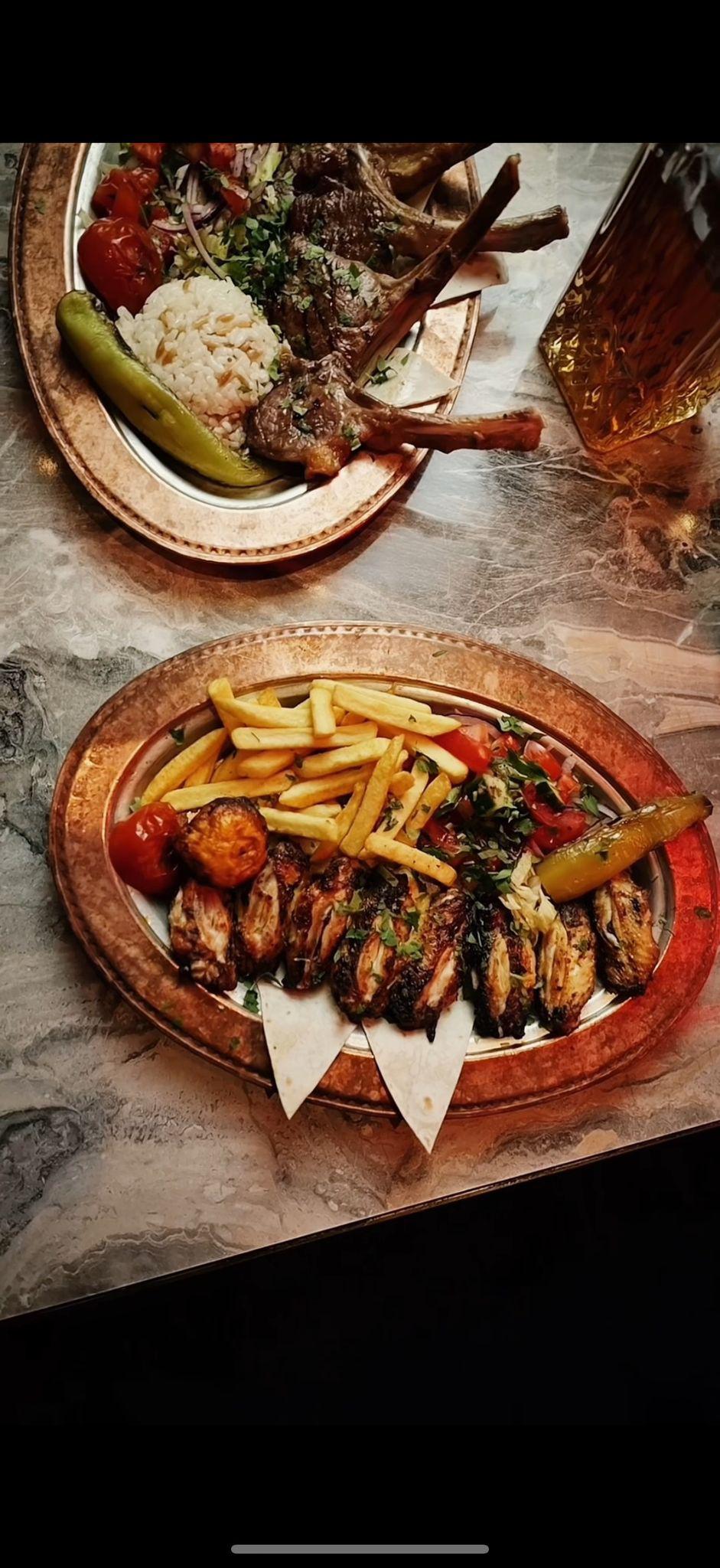Kupferteller mit Fleischspießen, Pommes, Reis, Tomaten und Gurken; rustikale Tischdekoration.